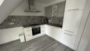 Eine Küche mit ornamental gestalteter Spritzschutzleiste, einem eingebauten Ofen und weißen Schränken.
