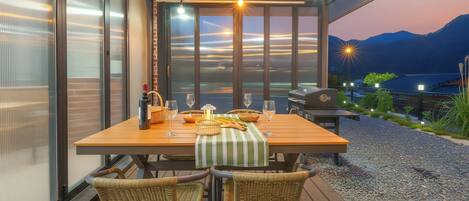 An outdoor dining area with a wooden table, wicker chairs, and a grill.