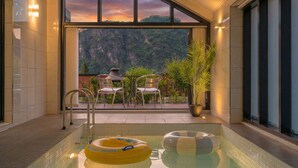 A pool area with a view of a mountainous landscape, a table with chairs, and a potted plant. - Danyang Dandelion Pool Villa (Danyang)