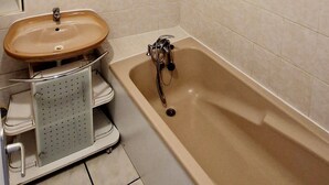 Kylpyhuone, jossa on pesuallas, peili ja kylpyamme.