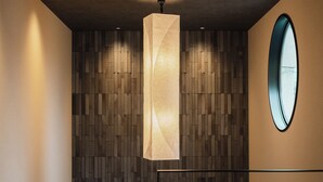 Un intérieur moderne agrémenté d’un luminaire aux formes géométriques, d’un mur à motifs et d’un miroir rond.