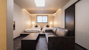 Une chambre d’hôtel moderne avec un canapé, deux lits, une table basse et une grande fenêtre.