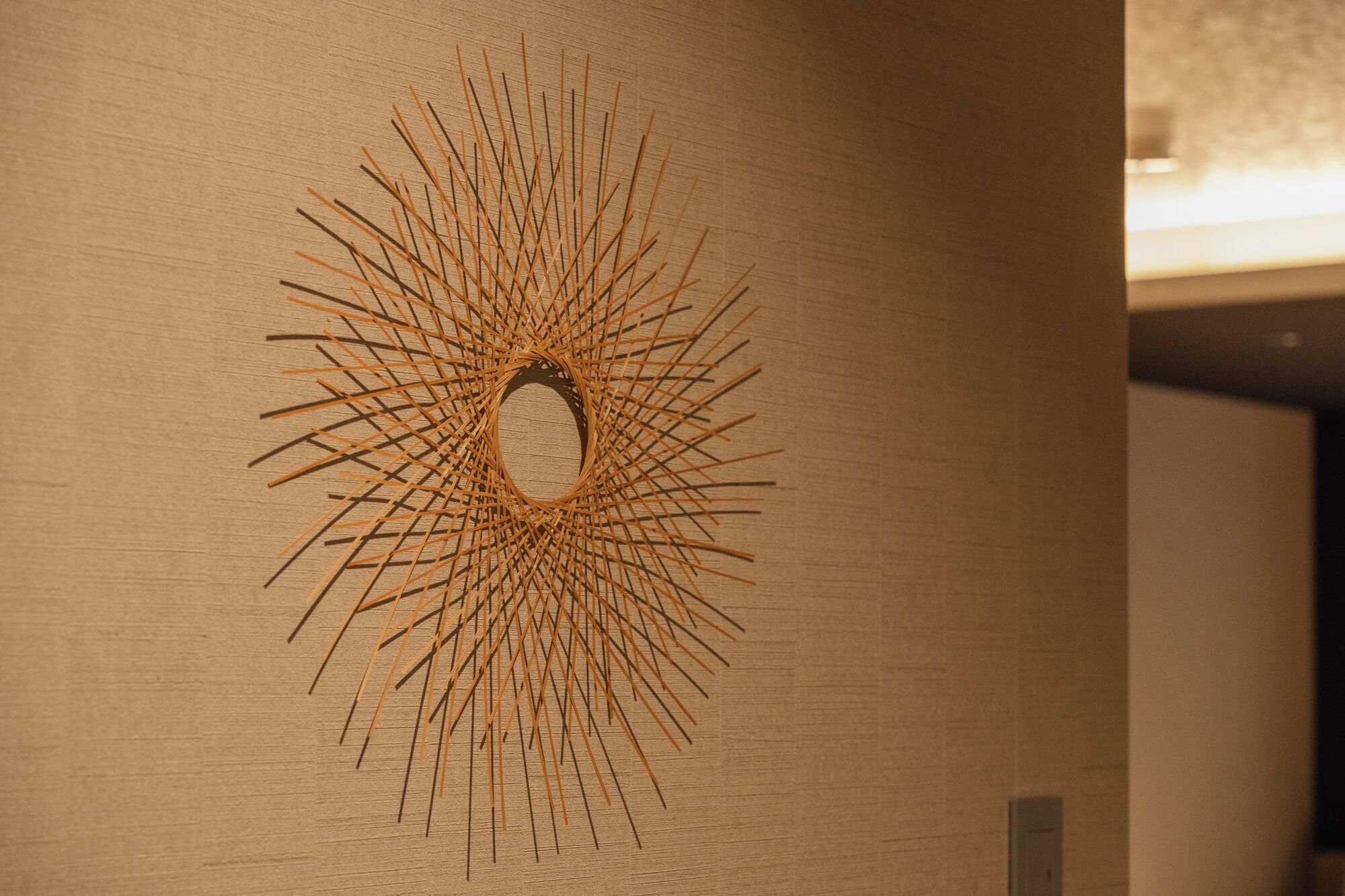 A wall with a circular design made of wooden sticks.
