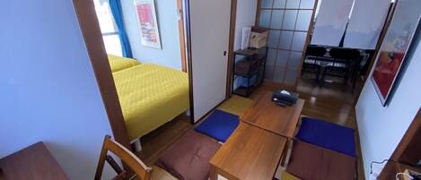 A traditional Japanese-style room with tatami flooring, a low wooden table, and a futon bed.