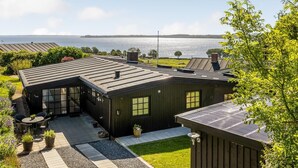 Una casa moderna con un amplio patio, vistas al agua y un jardín bien cuidado.