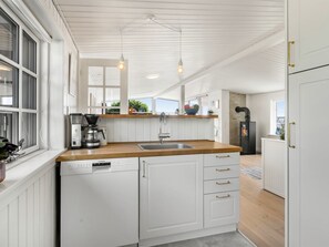 Eine moderne Küche mit weißen Schränken, einer Holz Arbeitsplatte, einem eingebauten Geschirrspüler und Pendelleuchten.