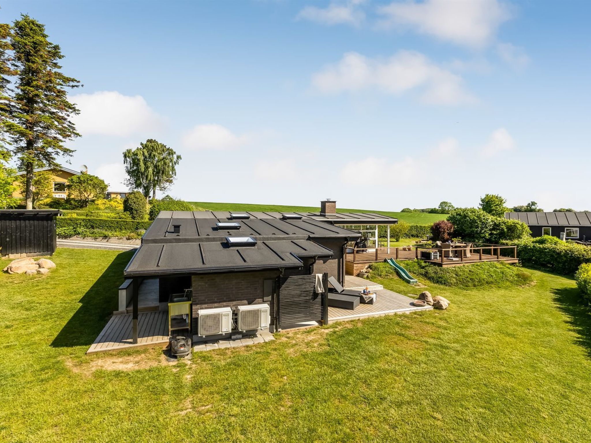 A modern house with a flat roof, a covered outdoor area, and a well-maintained lawn.
