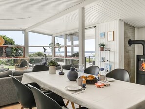 A dining area with a table set for breakfast, a view of the outdoors, and a wood-burning stove.