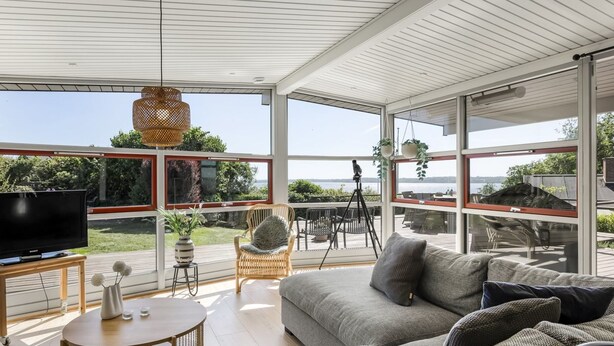 Una sala de estar moderna con un sofá grande, un televisor y una zona de comedor con sillas y una mesa.