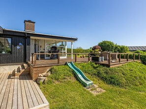 Ein modernes Haus mit Terrasse, Grillplatz und Rutsche.