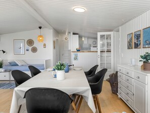 A modern kitchen with white cabinetry, a dining table with chairs, and a kitchen island.