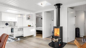 A modern, minimalist living space with a central wood-burning stove, white cabinetry, and a checkered floor. - "Myrte" - 300m from the sea by Interhome (Blokhus)