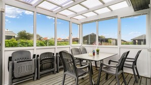A covered patio with a table and chairs, large windows, and a view of the surrounding area. - "Myrte" - 300m from the sea by Interhome (Blokhus)