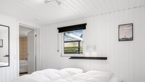 A bedroom with a bed, a window with a view, a mounted shelf, and a framed picture on the wall. - "Myrte" - 300m from the sea by Interhome (Blokhus)