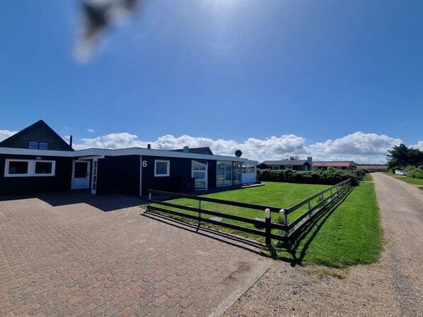 A building with a paved driveway, a fenced lawn, and a clear sky.