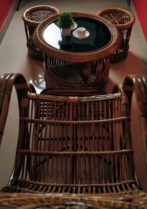 A wicker chair and a round table with a potted plant. - Hotel Meghnath Palace (Jalpaiguri)