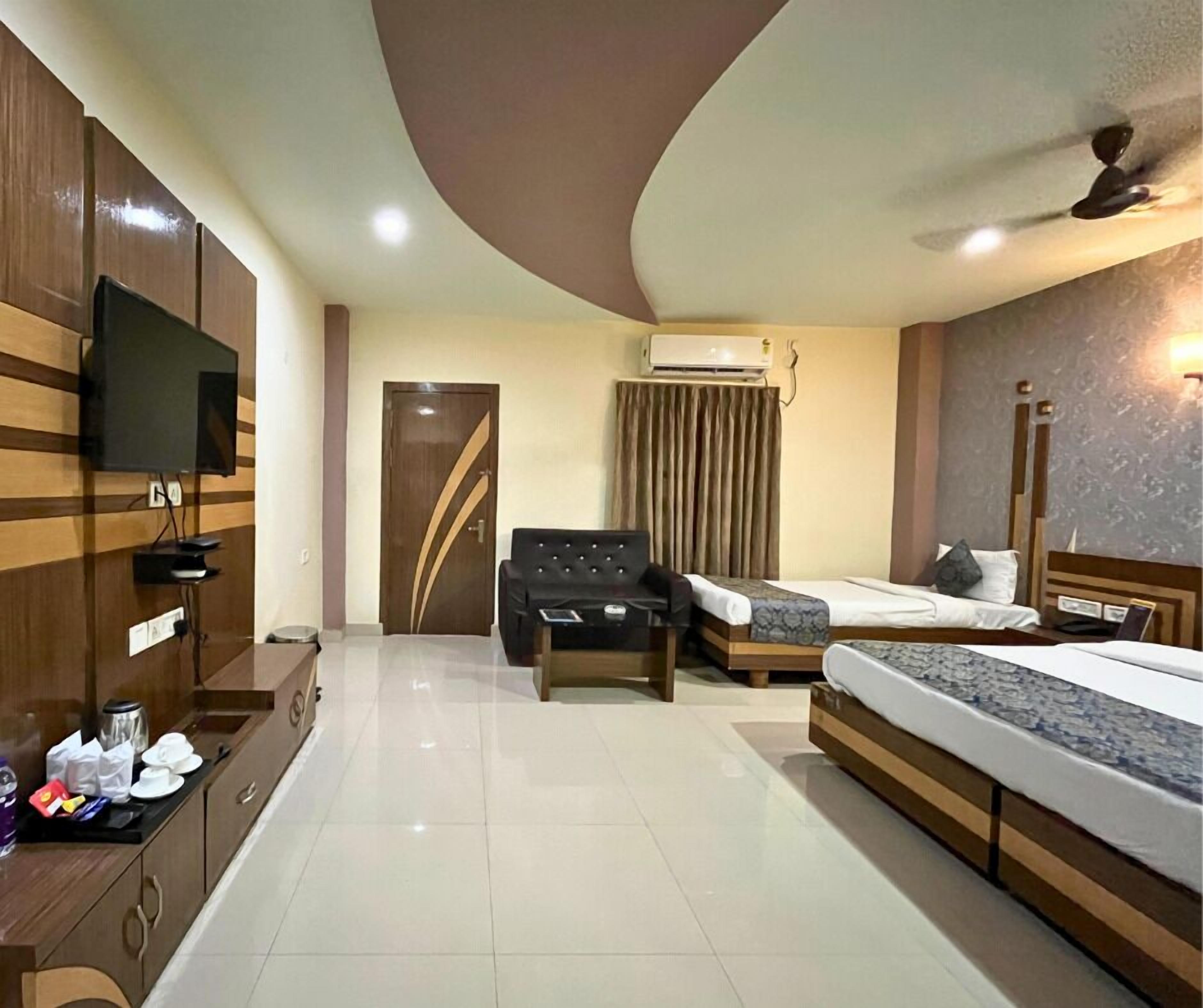 A hotel room with a bed, two bedside tables, a sofa, a TV, and a wardrobe.