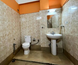 A bathroom with a toilet, sink, and mirror. - Hotel Meghnath Palace (Jalpaiguri)