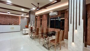 A modern dining area with a central table and chairs, a reception desk, and a ceiling fan. - Hotel Meghnath Palace (Jalpaiguri)