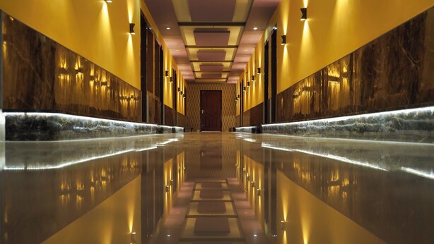 A long, reflective hallway with marble walls and lighting fixtures. - Hotel Meghnath Palace (Jalpaiguri)