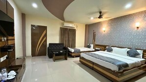 A modern hotel room with a large bed, a sofa, a desk, and a TV. - Hotel Meghnath Palace (Jalpaiguri)
