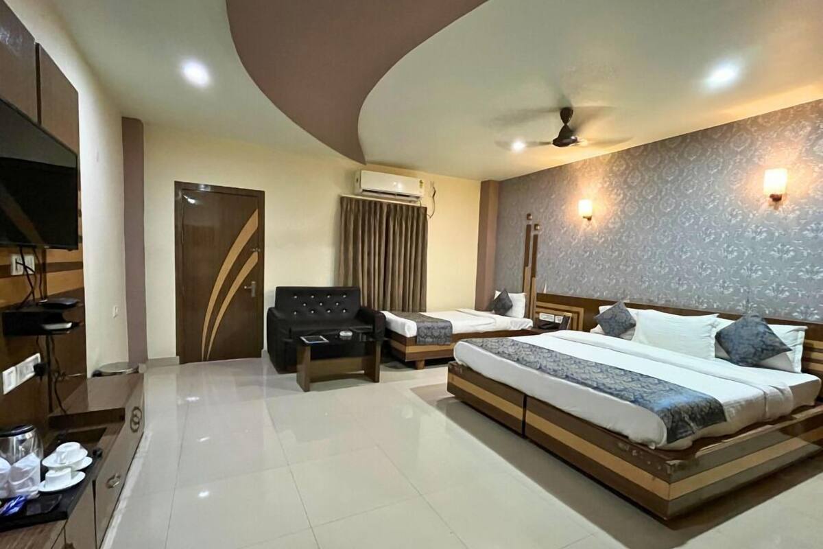 Quarto de hotel moderno com uma cama grande, um sofá, uma escrivaninha e uma televisão.