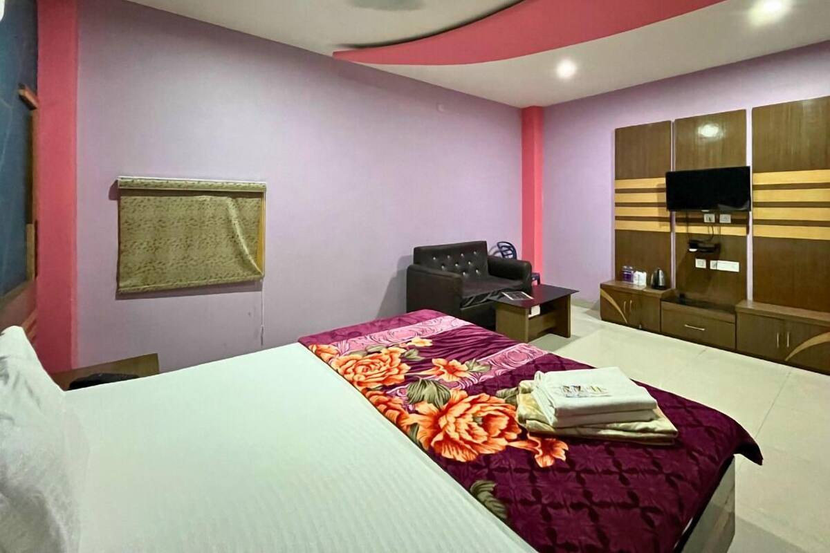 Um quarto com cama, escrivaninha, cadeira, televisão e guarda-roupa.
