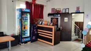Una zona de recepción con un refrigerador de Pepsi, un mostrador de madera y un letrero de salida de incendios.