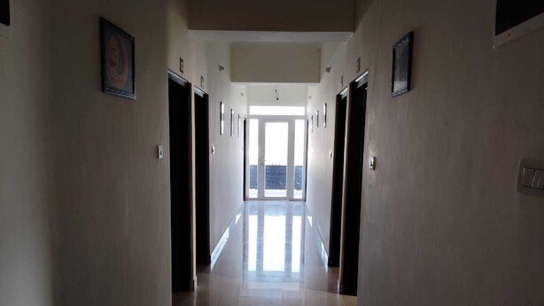 Un pasillo con puertas a ambos lados que conducen a una habitación luminosa con un ventanal grande.