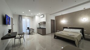 A modern hotel room with a bed, bedside table, and a desk with a laptop. - Pietra Viva - Suite & Relax (Veglie)