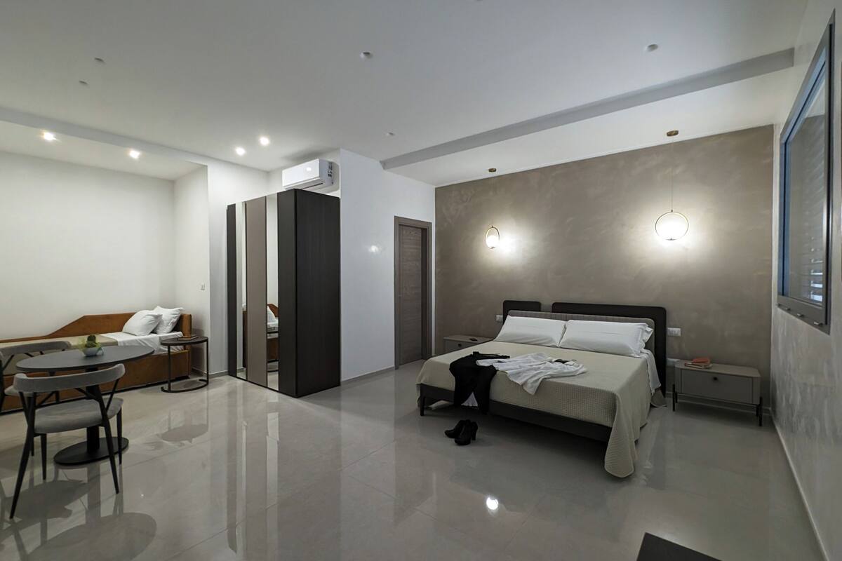 A modern hotel room with a bed, a sofa, a small table, and a chair.