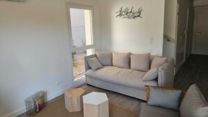 A modern living room with a beige sofa, a wooden coffee table, and a woven rug.