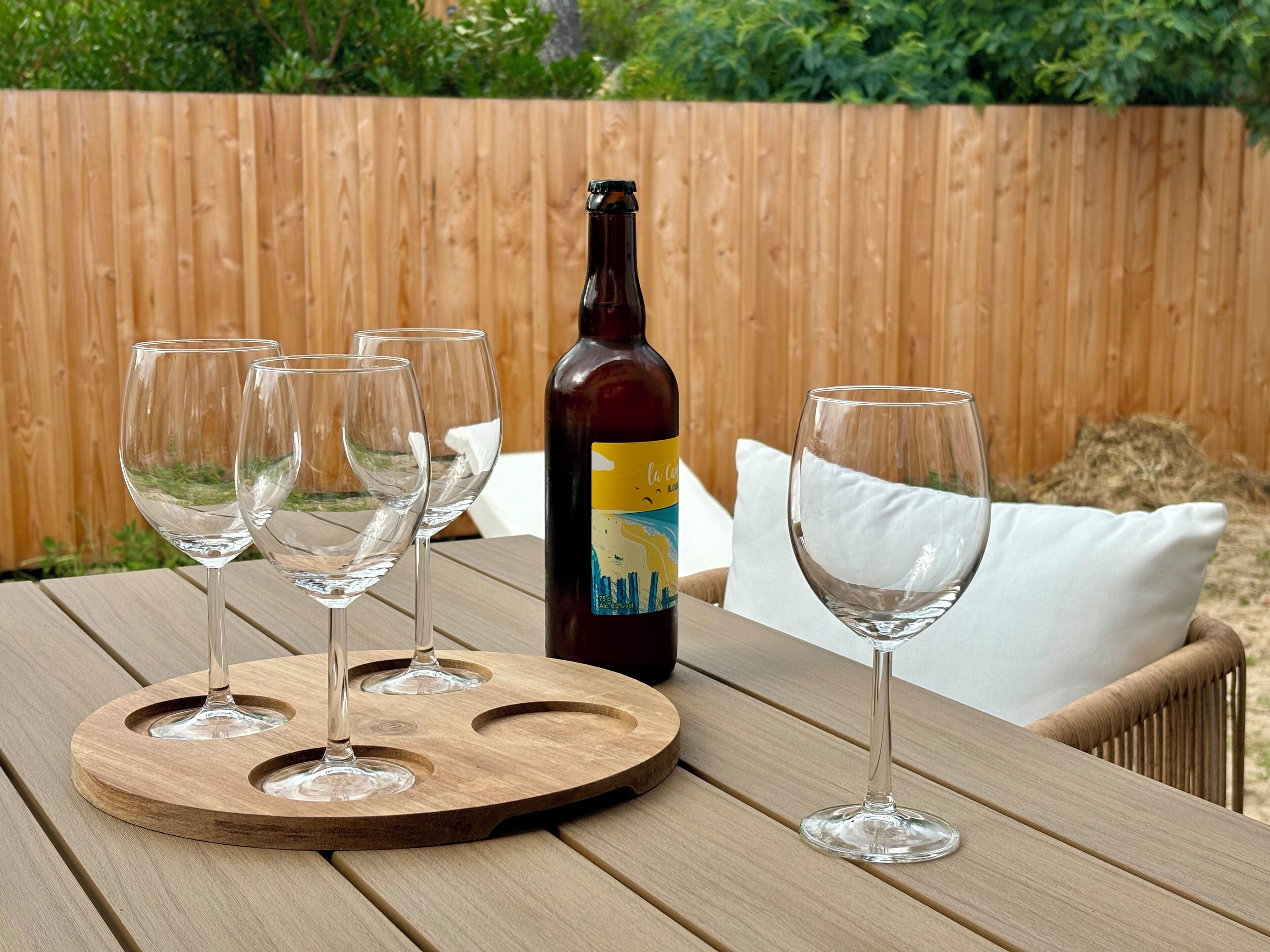 A wooden table with a bottle of wine and four wine glasses.