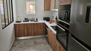 A modern kitchen with wooden cabinets, a stainless steel refrigerator, and a microwave.