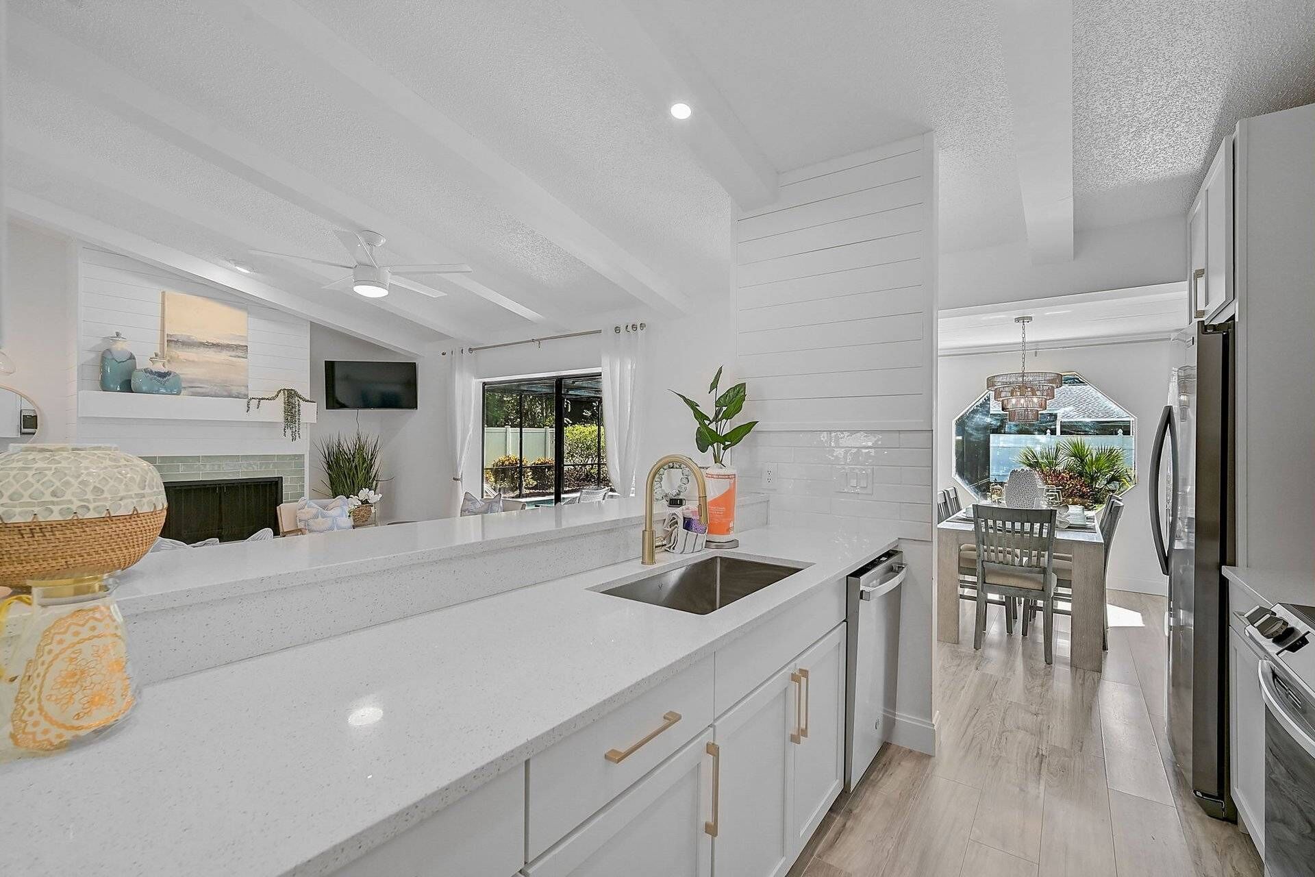 Een moderne keuken met witte kasten, een groot eiland en een eetgedeelte met een kroonluchter.