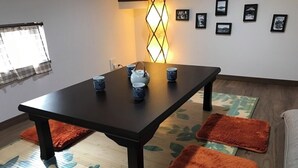 Un coin repas avec une table en bois foncé, quatre tasses bleues, une théière blanche et un luminaire décoratif.