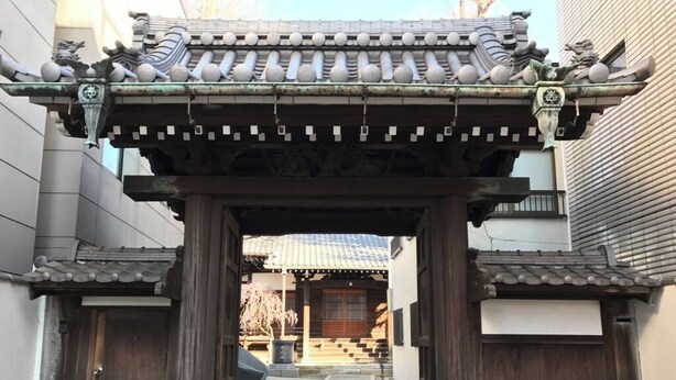 Une porte japonaise traditionnelle, avec des piliers en bois et un toit recouvert de tuiles.