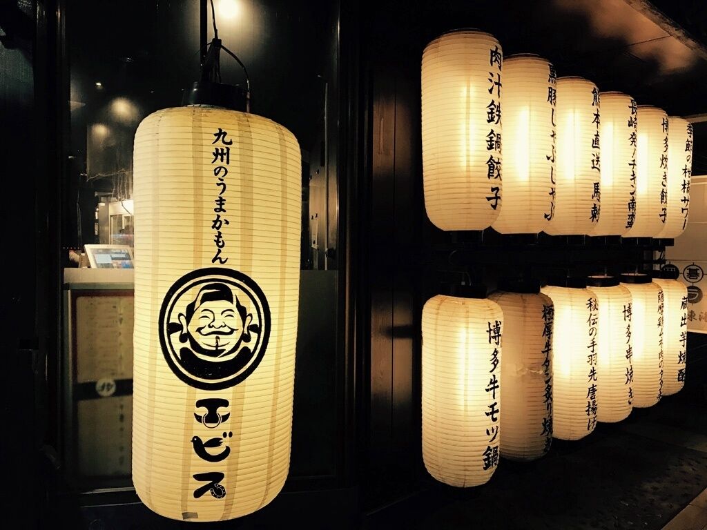 Eine Reihe traditioneller japanischer Papierlaternen mit Schriftzug, vermutlich hinweisend auf ein Restaurant oder eine kulturelle Einrichtung.