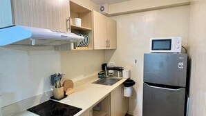 A compact kitchen with a built-in microwave, a stainless steel refrigerator, and a small countertop.
