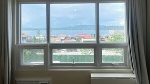 A room with a large window overlooking a body of water and distant mountains.