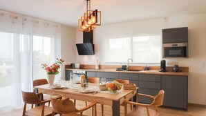 Una cocina moderna con una isla central, sillas de madera y una mesa de comedor preparada para cuatro.