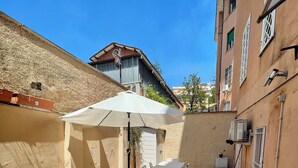 A patio area with a table and chairs, a white umbrella, and a potted plant. - A few steps from the historic center and Vatican (Roma)