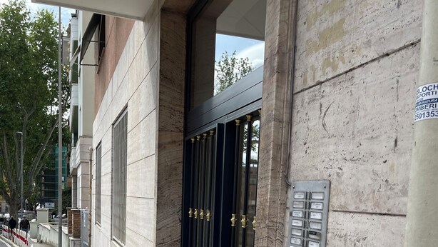 A building entrance with a dark metal gate, a concrete wall, and a metal panel with text. - A few steps from the historic center and Vatican (Roma)