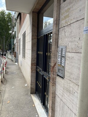 A building entrance with a dark metal gate, a concrete wall, and a metal panel with text. - Just a short walk from the historic center and the Vatican (Roma)