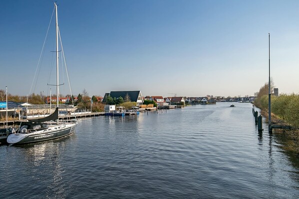 Enjoy a serene riverside setting with a sailboat docked nearby, perfect for relaxation and leisure activities.