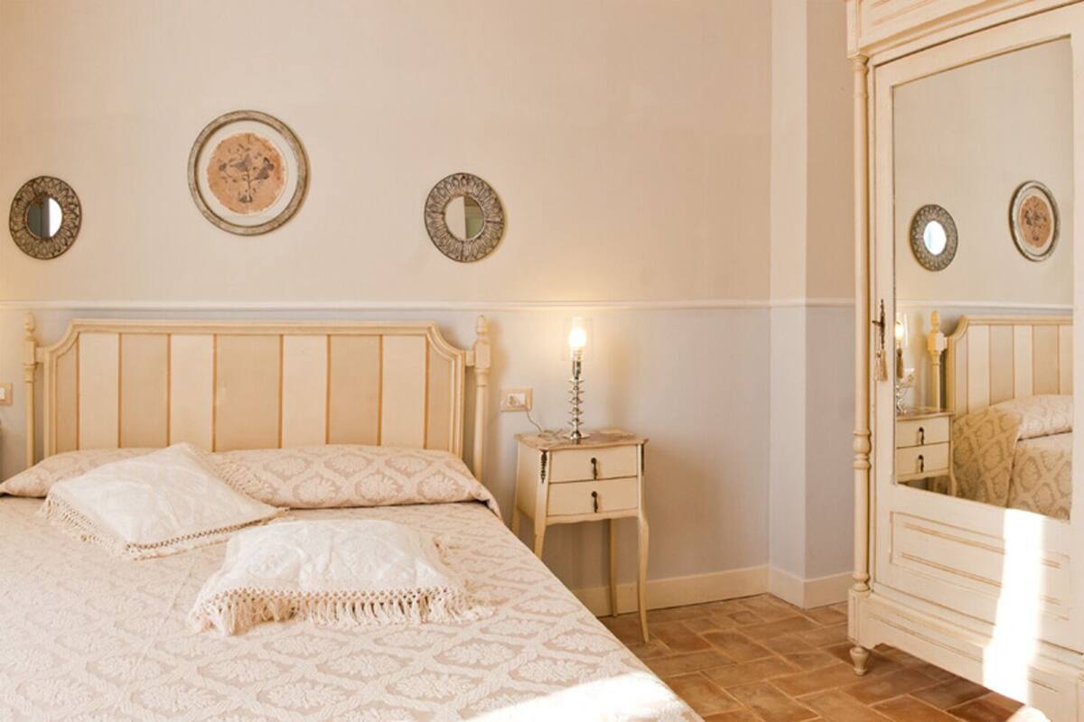 Een slaapkamer met een bed, nachtkastje, kledingkast en een stoel.