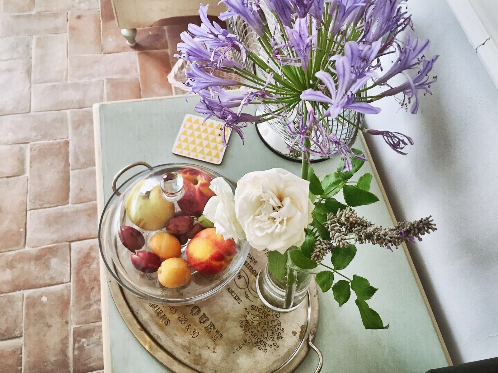 A tray with a glass jar containing peaches and a white rose.