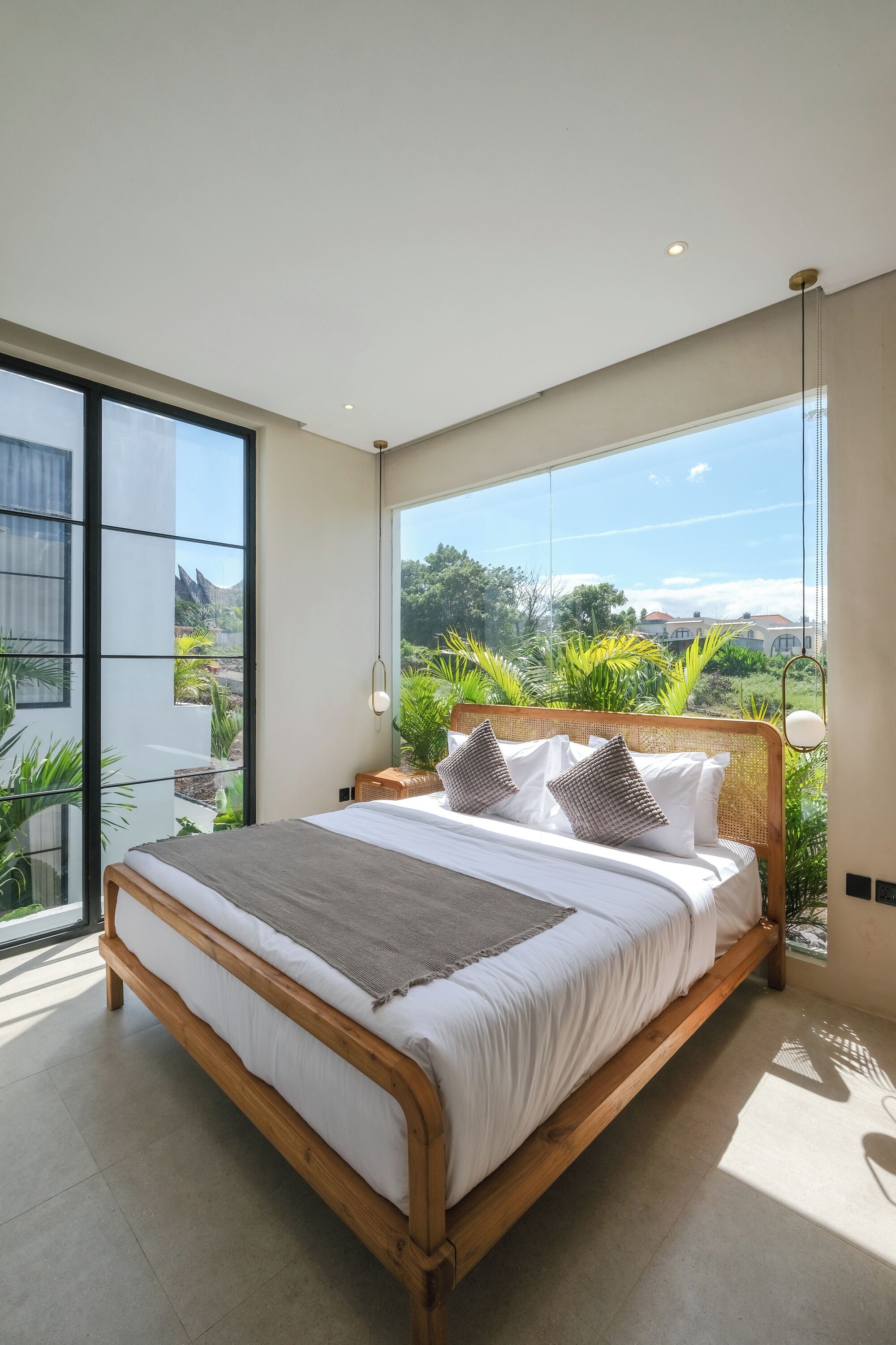 A modern bedroom with a large bed, a view of greenery, and a balcony.