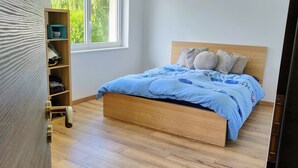 A bedroom with a wooden bed, a blue bedspread, and a wooden wardrobe.