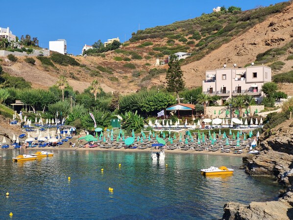 Une zone côtière avec une plage, des bateaux et une rangée de parasols.